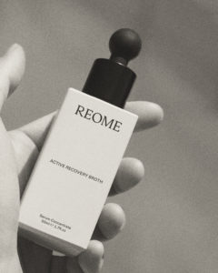 Black and white REOME bottle held in the palm of a hand