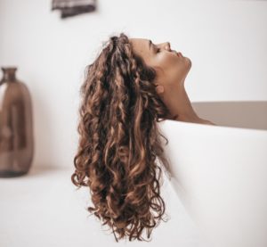 Woman lying in a bath relaxing with her hair hanging out