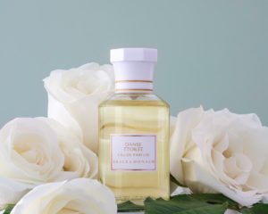 Grace de Monaco perfume bottle surrounded by white roses